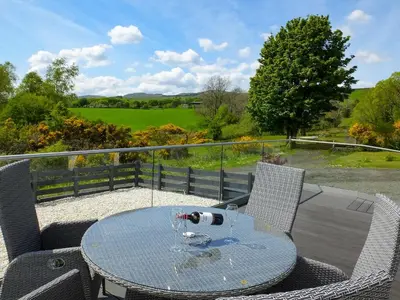 a glass table and chairs on a balcony with a view at Thistlebank in Banknock