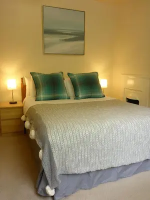a bedroom with a large bed with green pillows at Camus Bhan in Ballachulish