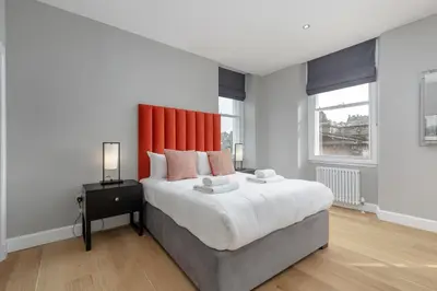 a bedroom with a large bed with an orange headboard at Destiny Scotland Hanover Apartments in Edinburgh