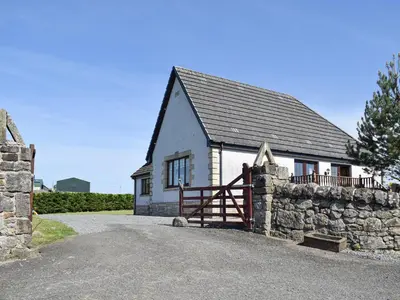 a small house with a stone wall and a gate at Lawford Lodge in Bonnybridge