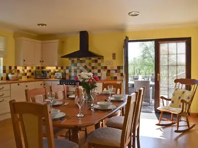 a kitchen with a wooden table with chairs and a dining room at Lawford Lodge in Bonnybridge