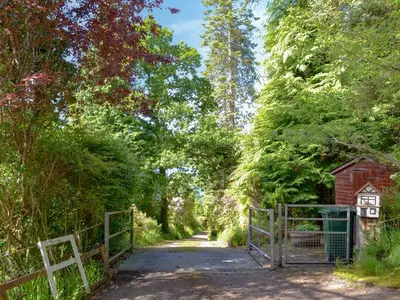 a wooden bridge with a gate and a small house on it at Dunyvaig in Colintraive