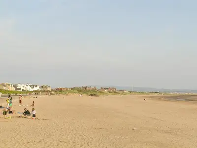 a group of people sitting on a beach at Tigh Beag in Troon