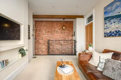 a living room with a couch and a brick wall at Stylish & Central 2BR Stockbridge Gem in Edinburgh