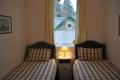 two twin beds in a room with a window at Auchmore Apartments in Killin