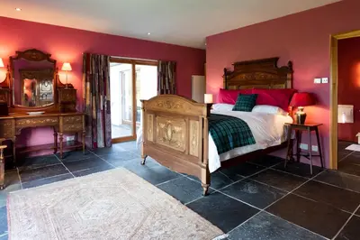 a bedroom with a large bed with red walls at Powdermills B & B in Inveraray