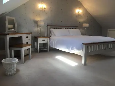 a bedroom with a large white bed and a tv at South Doll Farm Cottage in Airth