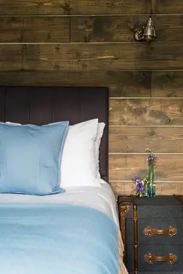 a bed with blue and white pillows and a wooden wall at The Kilchrenan Inn in Oban