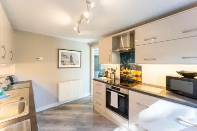 a kitchen with white cabinets and a stove top oven at Gleneagles Apartment - Guthrie Court Gleneagles in Auchterarder