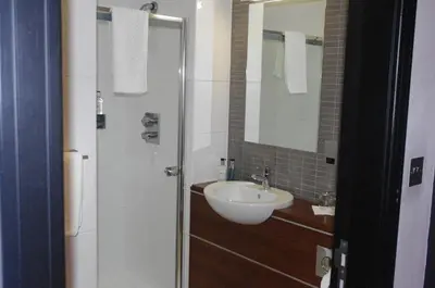 a bathroom with a sink and a shower with a mirror at Fletcher's Restaurant Bar & Rooms in Stirling