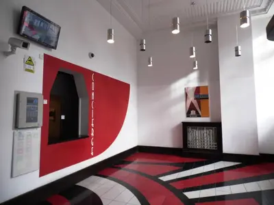 a room with a tv and a red and white wall at Art Deco Building on Vibrant Sauchiehall Street in Glasgow