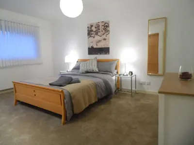 a bedroom with a bed with a dresser and a mirror at Modern 2-bedroom Apt near SSE Hydro and SEC in Glasgow