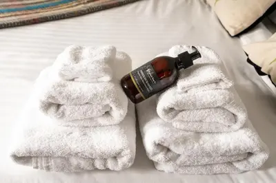 a pair of white towels with a bottle of alcohol at Cardross Inn in Cardross