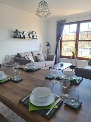 a living room with a wooden table with plates and wine glasses at Six Stevenson House, Oban in Oban
