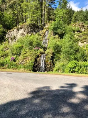 a road with a waterfall on the side of a mountain at Lyndhurst 39 in Dunoon