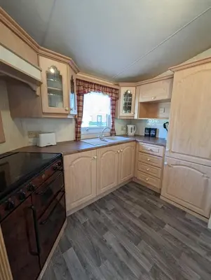 an empty kitchen with wooden cabinets and a sink at Lyndhurst 39 in Dunoon