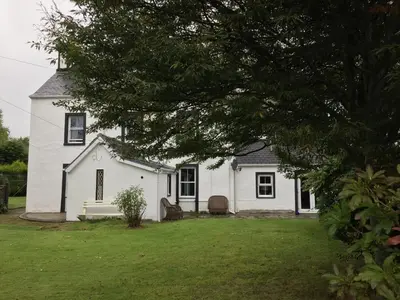 a white house with a tree in front of it at Kilmory Garden by the Loch in Lochgilphead