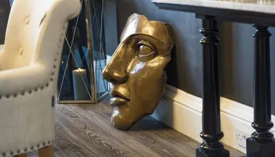 a gold head statue on the floor next to a table at Ram Lodge in Moffat