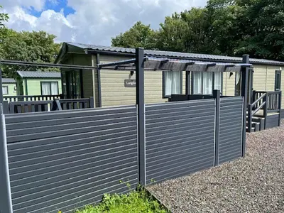 a wooden fence in front of a house at Lomond Woods Holiday Park in Balloch