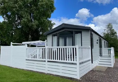 a white tiny house with a black roof at Lomond Woods Holiday Park in Balloch