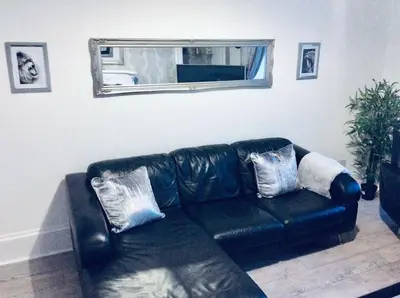 a black leather couch in a living room with a mirror at THE LION'S DEN ON ROYAL STREET in Gourock