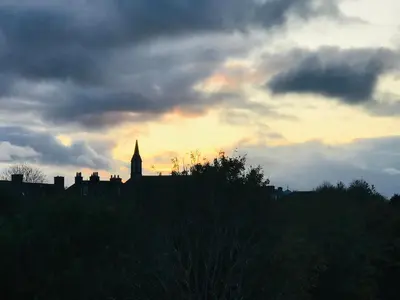 a silhouette of a building with a clock tower in the sunset at “A Wee Pad in Dunfermline” in Dunfermline