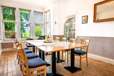a dining room with a wooden table and chairs at The Woodhouse Hotel in Largs