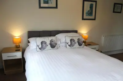 a bedroom with a white bed with three photographs on pillows at The Woodhouse Hotel in Largs