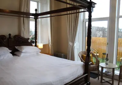 a bedroom with a canopy bed and a window at The Woodhouse Hotel in Largs