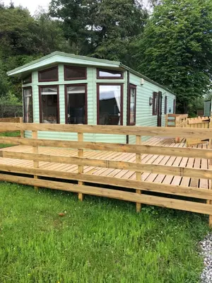a green trailer with a fence in front of it at The Aspen 63 in Dunoon