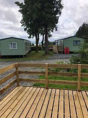 a wooden fence next to two mobile homes at The Aspen 63 in Dunoon