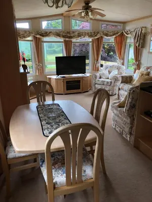 a living room with a table and chairs and a television at The Aspen 63 in Dunoon