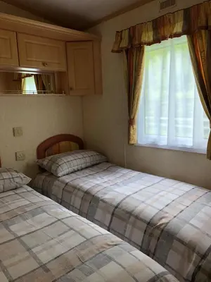 two beds in a room with a window at The Aspen 63 in Dunoon