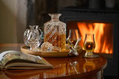a table with glasses and a bottle of wine and a book at The Farmhouse B&B in Dunkeld