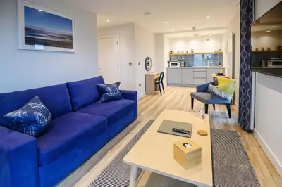 a living room with a blue couch and a table at The Salt Lodge in Troon