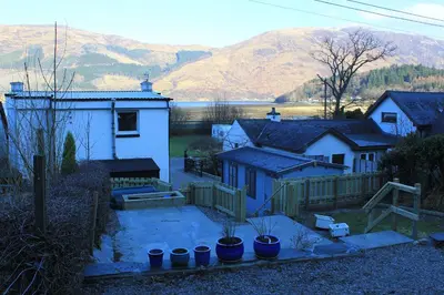 a group of houses with mountains in the background at Arivonie Lochside Cottage in Glencoe