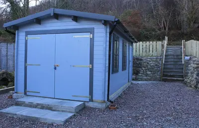 a blue out house with a set of stairs at Arivonie Lochside Cottage in Glencoe