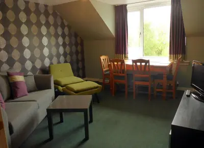 a living room with a couch and a table and chairs at Arivonie Lochside Cottage in Glencoe