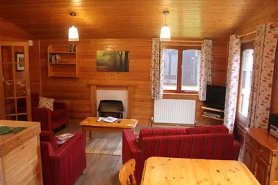 a living room with red couches and a fireplace at Rowan Tree Lodge in Glencoe