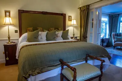 a large bedroom with a large bed and a chair at Kilmeny in Ballygrant