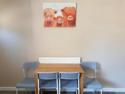 a table with chairs and a painting of cows at The Abercromby Townhouse - Close to Merchant City in Glasgow