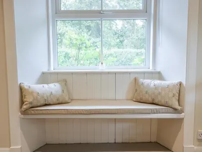a window seat with two pillows sitting under a window at Gate Lodge in West Calder