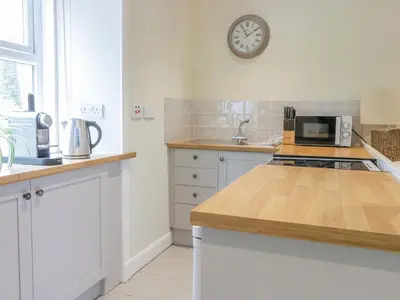 a kitchen with white cabinets and a clock on the wall at Gate Lodge in West Calder