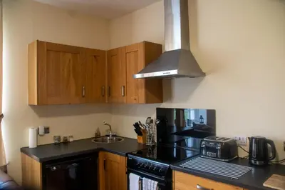 a kitchen with wooden cabinets and a black stove top oven at Kilchrist Castle Cottages in Campbeltown