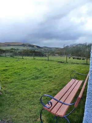 a wooden bench sitting in a field of grass at Kilchrist Castle Cottages in Campbeltown