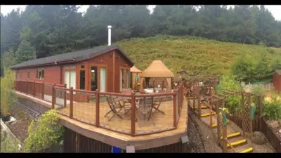 a small house with a playground in front of a hill at Ramintoul Lodge in Glendevon