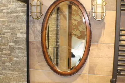a mirror on a wall with two lights on it at The Victoria Inn Blythswood Snug in Falkirk