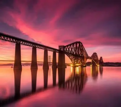 a bridge over the water with a sunset at The Victoria Inn Blythswood Snug in Falkirk