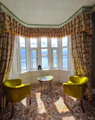 a room with two chairs and a table and a window at Corriemar House in Oban