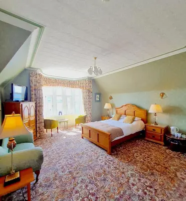 a bedroom with a bed and a chair and a window at Corriemar House in Oban